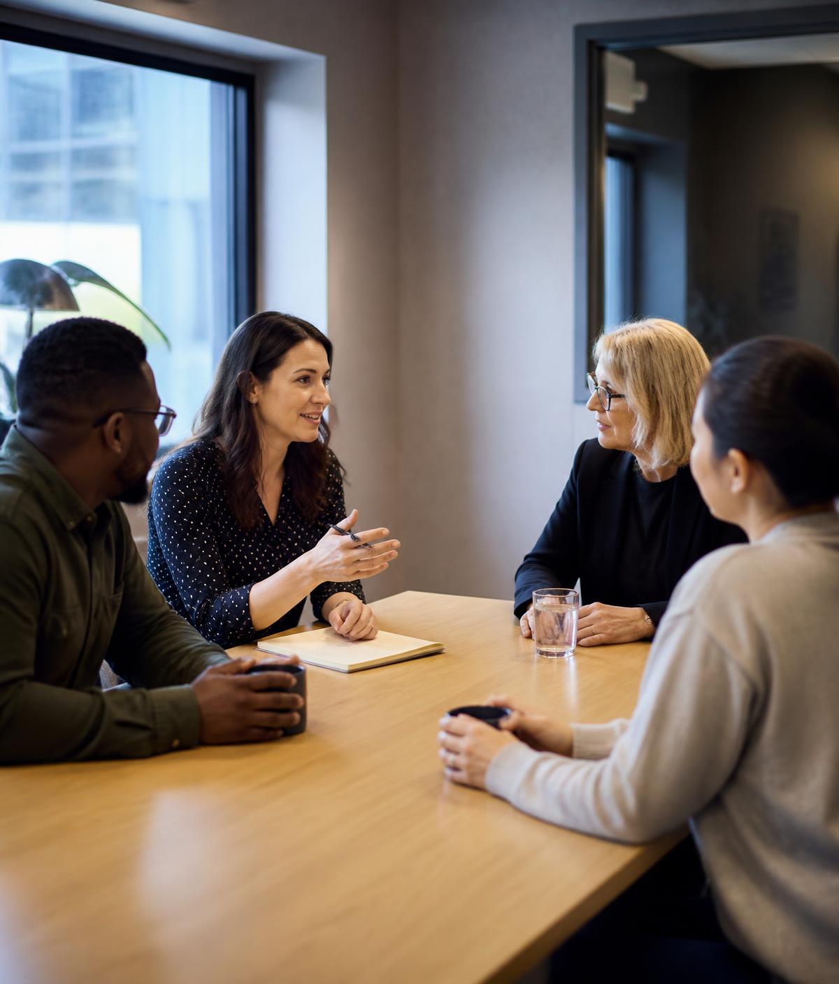 Four business professionals in discussion around a table in a modern focus group research room